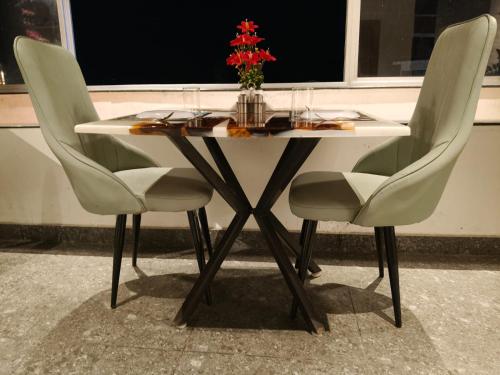 a table with two chairs and a vase of flowers on it at Hotel Landmark in Port Blair