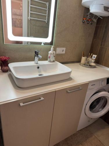 a bathroom with a sink and a washing machine at VIP Apartments 57 in Odesa