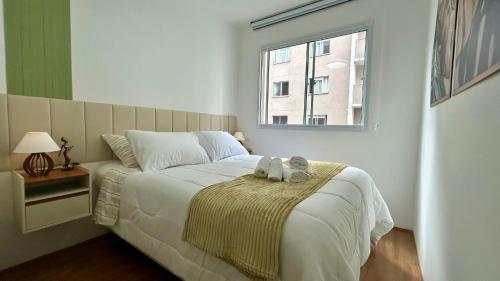 a bedroom with a bed with two cats sitting on a blanket at O mais completo Studio com sacada prox Tokio Marine Hall in Sao Paulo
