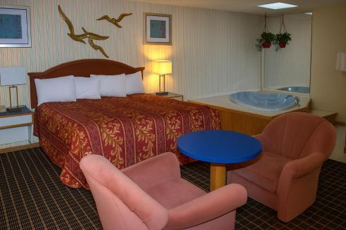 a hotel room with a bed and two chairs at Ventura Motel in Ludington
