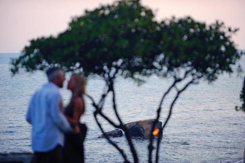 a man and a woman kissing next to the water at Luna Sardinia in Santa Margherita di Pula