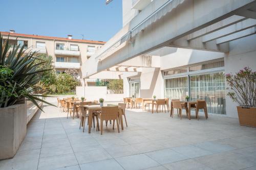 a patio with tables and chairs in a building at Zenitude Hôtel Résidences Nice in Nice