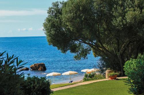 a beach with umbrellas and the ocean at Luna Sardinia in Santa Margherita di Pula