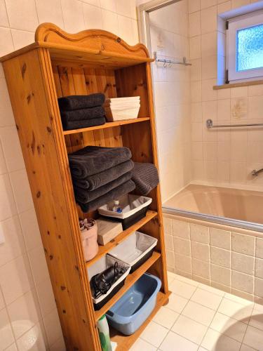 a wooden shelf in a bathroom with towels and a tub at Ferienwohnung Gisela in Kolbermoor