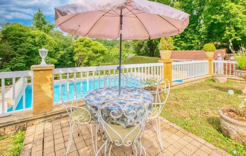 une table avec un parasol à côté d'une piscine dans l'établissement 3 Bedroom Gorgeous Home In Le Lardin, à La Villedieu