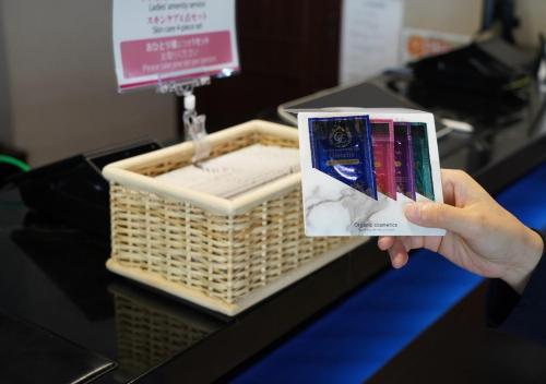 a person holding up a book in front of a basket at Hotel New Gaea Ube in Ube