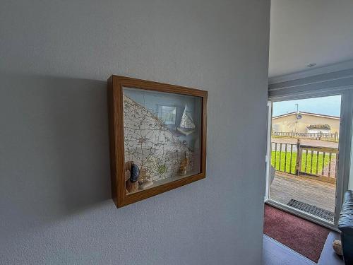 a picture hanging on a wall next to a window at Chalet For Hire At Rainbows End Near A Beautiful Norfolk Beach Ref 31039R in Bacton