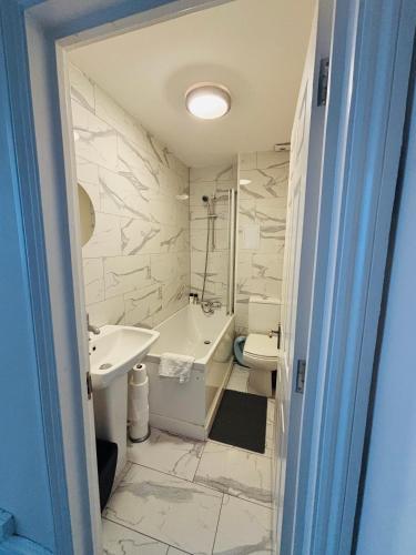 a bathroom with a tub and a sink and a toilet at Moat Stays Victorian, Sea View! in Kent
