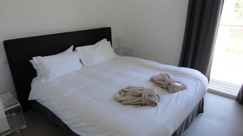 une chambre avec un lit avec deux pantoufles dessus dans l'établissement La corse les pieds dans l'eau, à Pinarellu