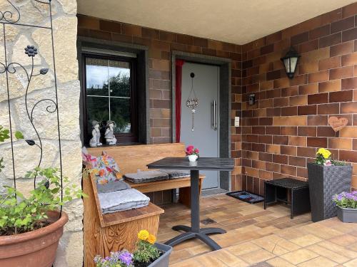 eine Terrasse mit einem Tisch und einer Bank auf einer Backsteinmauer in der Unterkunft Ferienwohnung Thiel in Neumark