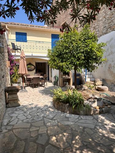 un patio avec une table et un arbre et un bâtiment dans l'établissement La fleur d'oranger, à Aigues-Mortes