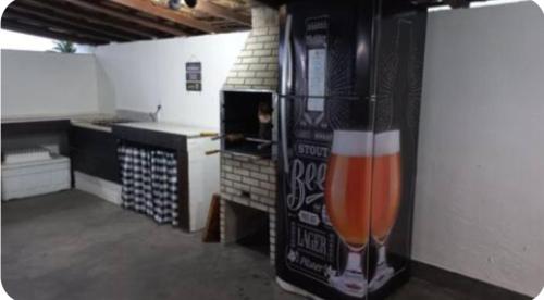 une grande bouteille de boisson est accrochée au mur d'une cuisine dans l'établissement Casa Pé na Areia Praia de Piratininga, à Niterói