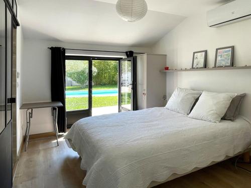 a bedroom with a bed and a large window at Maison de charme avec piscine, escapade, détente in La Rochelle