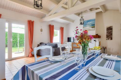 une salle à manger dotée d'une table avec un chiffon bleu et blanc dans l'établissement Jardin - Centre Noirmoutier - Maison pour 4, à Noirmoutier-en-l'lle
