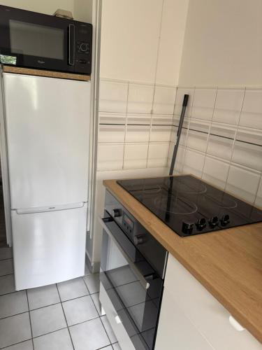 une cuisine avec une cuisinière et un réfrigérateur dans l'établissement Spacieux 3 pièces Balcon Rive gauche de la Seine, à Issy-les-Moulineaux