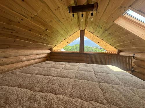 a large bed in a wooden room with a window at Cabana de la Stână in Râşnov