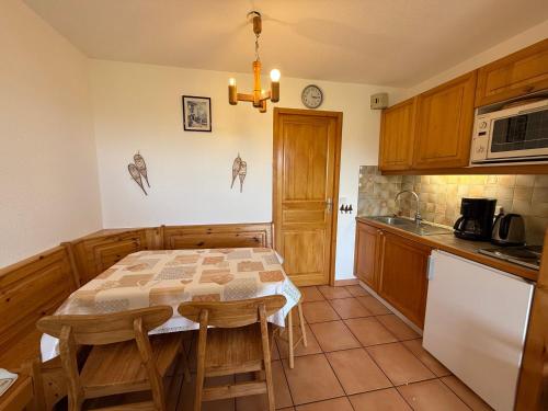 une cuisine avec une table, un four micro-ondes et un comptoir dans l'établissement Les Saisies: Studio cabine 5 pers avec balcon, TV et casier à skis - FR-1-293-130, aux Saisies