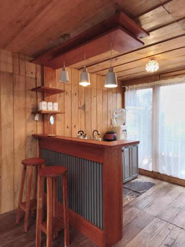 a kitchen with wooden walls and a counter with stools at Kizuna villa in Dieng