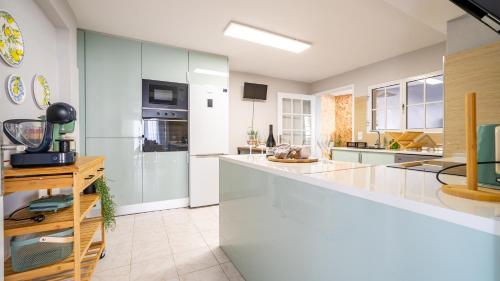 a large kitchen with white counters and appliances at Family House in Campanário