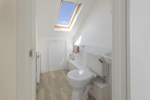 a white bathroom with a toilet and a sink at Rooftop Hideaway -Central Coastal Flat - Sea Views in Seaton