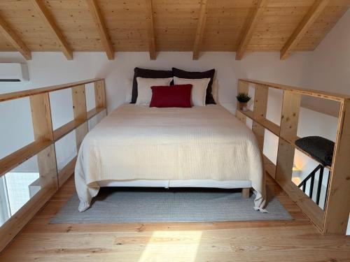 a bedroom with a large bed with a red pillow at Casas do Mercado, 5 in Montemor-o-Novo