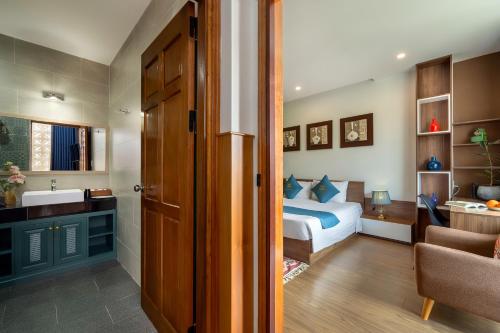 a bedroom with a bed and a bathroom with a sink at Square Villa Hoi An in Hoi An