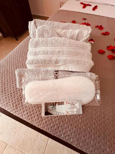 a bed with white towels and red flowers on it at Aca Suite Luxury in Adelfia