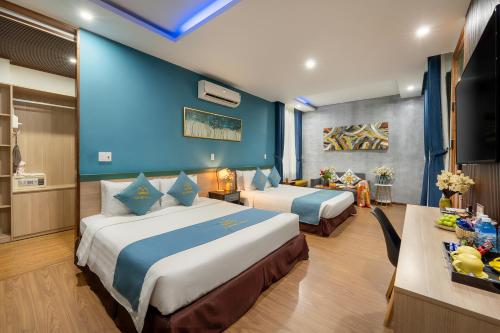 a hotel room with two beds and a blue wall at Square Villa Hoi An in Hoi An