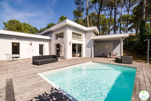 une maison avec une piscine devant une maison dans l'établissement Villa Familiale avec Piscine 10 pers Biscarrosse, à Biscarrosse