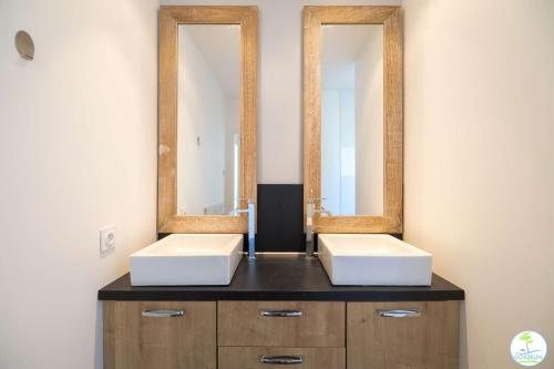 une salle de bains avec deux lavabos et deux miroirs sur un comptoir dans l'établissement Villa Familiale avec Piscine 10 pers Biscarrosse, à Biscarrosse