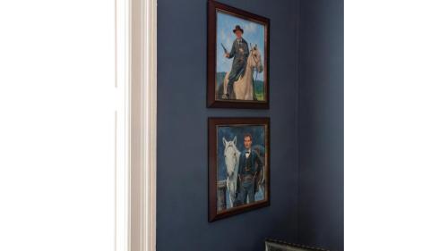 three framed paintings on a blue wall in a room at Jesse James - Historic Hotel in Cimarron