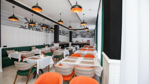 a dining room with white tables and orange chairs at Cardinal in Quba