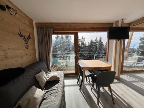 a living room with a couch and a table at Très bel appartement exposition sud classé 3 étoiles in Chamrousse
