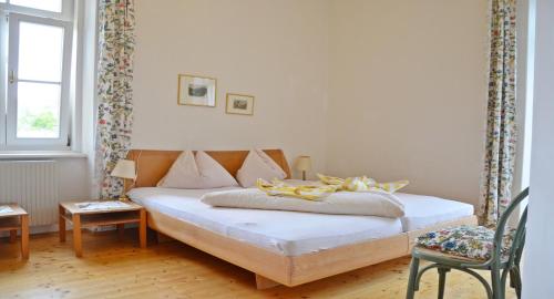 a bedroom with a bed and a chair and a window at Hotel Seehof in Maria Wörth