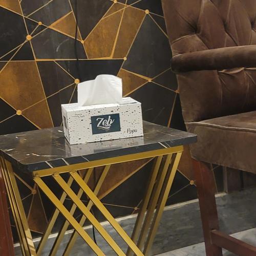 a box of kleenex on a table next to a chair at Guest House in Karachi