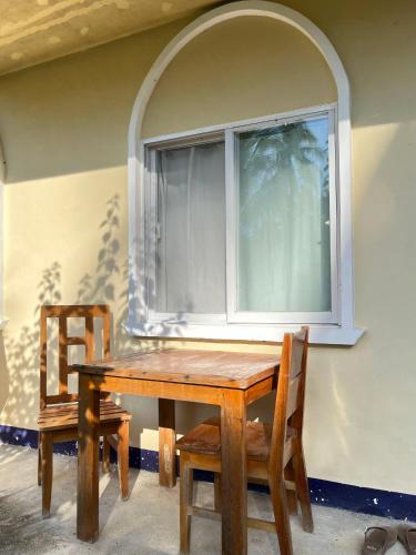 a wooden table with two chairs and a window at JMJ Homestay, near Magpupungko Rock Pools in Pilar