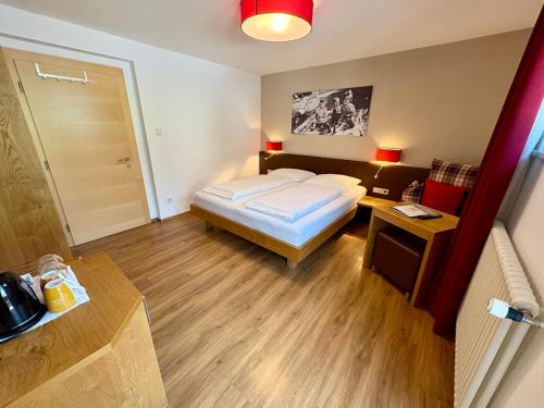 a bedroom with a bed and a table and a door at Garni Apparthotel St Valentin in San Valentino alla Muta
