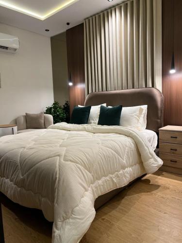 a bedroom with a large white bed with green pillows at Quiet studio with comfortable hotel bed in Riyadh