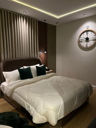 a bedroom with a large bed with a clock on the wall at Quiet studio with comfortable hotel bed in Riyadh
