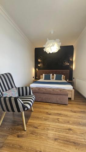 a bedroom with a bed and a chair and a chandelier at Black Room Apartment in Mukacheve