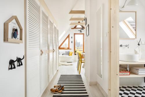 a hallway with white walls and a black and white rug at TatryTop Zakopiańskie Tarasy Premium & SPA in Zakopane