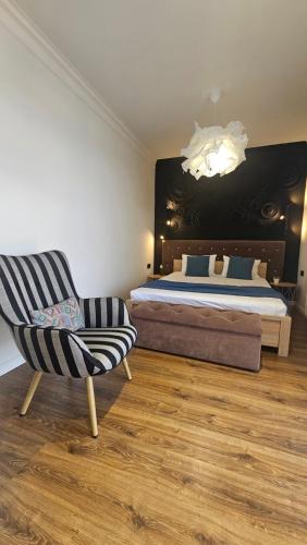 a bedroom with a bed and a chair and a chandelier at Black Room Apartment in Mukacheve