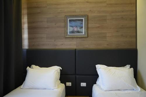 two beds with white pillows in a hotel room at BluePoint Hotel in Tepelenë