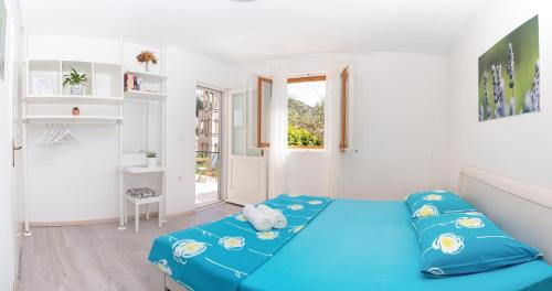 sypialnia z niebieskim łóżkiem w białym pokoju w obiekcie Apartments Olive Tree w Hvarze