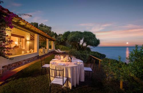 a dining table on a patio with a view of the ocean at Luna Sardinia in Santa Margherita di Pula