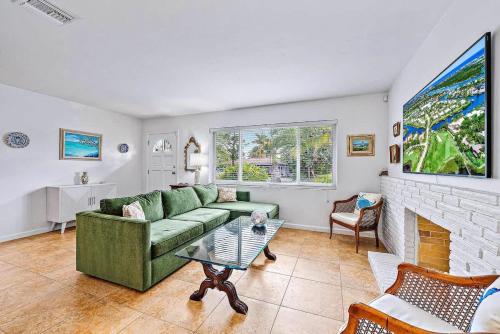 a living room with a green couch and a fireplace at Casa Balsinde - Delight in a Private Pool in the Southern End of West Palm in West Palm Beach