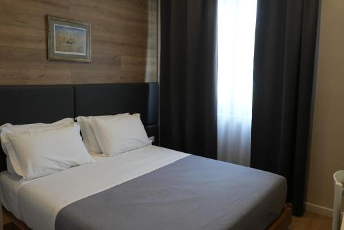 a bedroom with a bed with white sheets and a window at BluePoint Hotel in Tepelenë