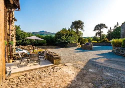 a patio with a table and chairs and an umbrella at Peaceful Barn Near Cader Idris in Dolgellau
