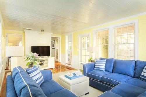 a living room with blue couches and a tv at Casa Paradiso - A Sun Drenched Escape with Poolside Cabana Charm in West Palm Beach