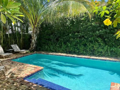 a swimming pool in a yard with a palm tree at Casa Paradiso - A Sun Drenched Escape with Poolside Cabana Charm in West Palm Beach